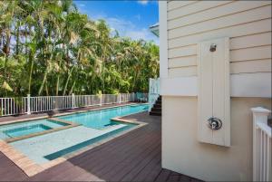 a swimming pool next to a house with palm trees at Sunset & Sand townhouse in Anna Maria Island