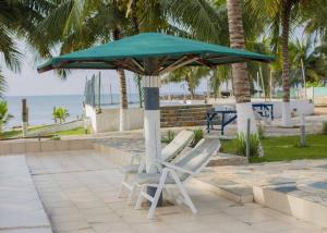 two lounge chairs under an umbrella next to the beach at LLOYDS BEACH RESORT and SPA in Kokrobite