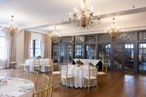 a dining room with white tables and chairs and chandeliers at The Mimslyn Inn in Luray