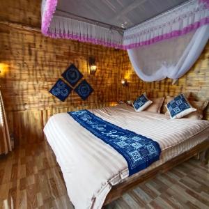 un dormitorio con una cama con mosquitera en Nhà Cổ Lao Xa Homestay Hmong & Bungalow air conditioner, en Dồng Văn