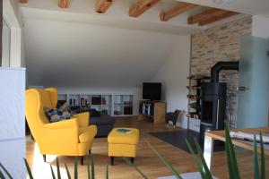 ein Wohnzimmer mit einem gelben Stuhl und einer Couch in der Unterkunft Premium Ferienloft Dreßler Fulda in Fulda