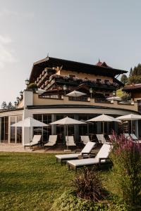 a building with white lounge chairs and umbrellas at Appartements Gut Berg in Sankt Johann im Pongau