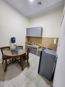 a kitchen with a table and a table and a refrigerator at Anugrah Syariah Homestay Ciperna in Cirebon