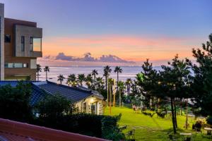 a view of a building and the ocean at sunset at Hold in Hamdeok with beach in Jeju