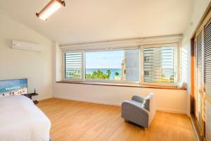 a bedroom with a bed and a chair and a large window at Hold in Hamdeok with beach in Jeju