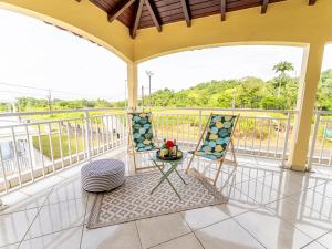 a balcony with two chairs and a table at Haut de villa Solèy Rivyè- 3 chambres in Petit-Bourg