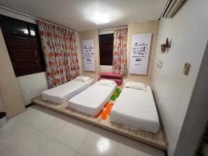 two beds in a room with two windows at Rey House in Satuba
