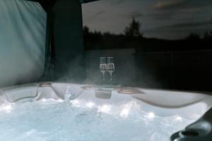 a bath tub with two wine glasses in it at Aura Wellness Apartment in Vrbno pod Pradědem