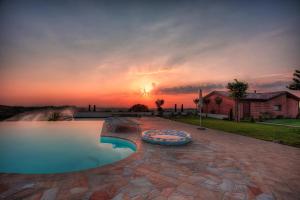 a pool in a backyard with a sunset in the background at Le Orchidee Villa in Roncofreddo