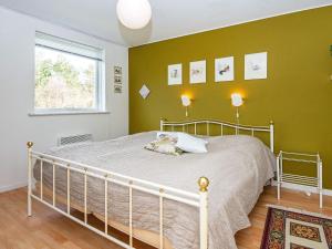 a bedroom with a bed with green walls and a window at 8 person holiday home in Løgstør in Løgsted
