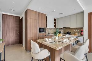 a kitchen with a large island with white chairs at GYL Holiday Homes -Imperial Avenue - Luxury Retreat Apt with Burj Khalifa Pool View - Near Dubai Mall in Dubai