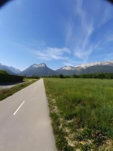 a road leading into a field with mountains in the background at La Grange in Doussard +12 photos