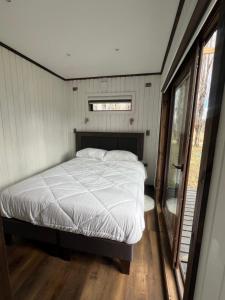 a bed in a small room with a window at Cabaña entre alamos in Coihaique