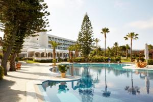a large swimming pool with palm trees and a building at ROBINSON KYLLINI BEACH - All Inclusive in Kyllini