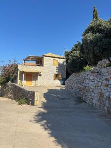 a house with a stone wall next to a sidewalk at Villa Panόrama in Riglia