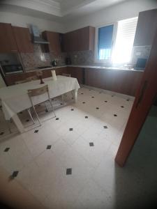 a kitchen with a table and a white tiled floor at R flaurence la marsa in El Haouach