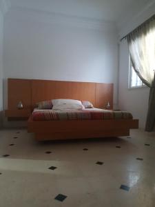 a bedroom with a large bed with a wooden headboard at R flaurence la marsa in El Haouach