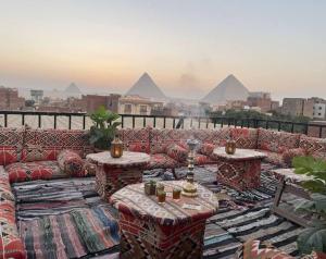 a rooftop patio with couches and tables and the pyramids at Bedouin Camp pyramids view INN in Cairo