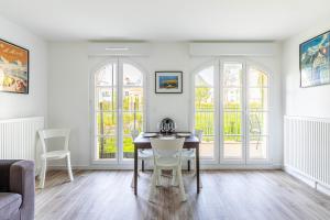 Un comedor con mesa y sillas y ventanas. en GuestReady - Charming getaway near Disneyland, en Marne-la-Vallée