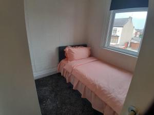 a small room with a bed with a window at Modern Seaside Stay at Bela Grove-Sleeps8 in Blackpool +3 photos