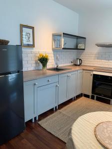 a kitchen with white cabinets and a black refrigerator at Apartament Ogrodowa in Bielany Wrocławskie