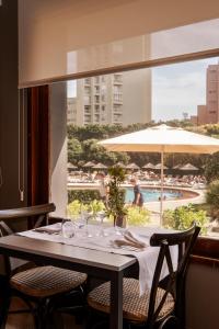 a table with wine glasses and a view of a pool at Axis Vermar Conference & Beach Hotel in Póvoa de Varzim