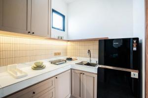 a kitchen with a black refrigerator and a sink at Le Jardin CoLiving B3 - Upscale Apt, Canggu center in Canggu