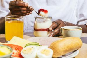 una persona che mangia uova e pane tostato con un barattolo di latte di Point A Hotel London Shoreditch a Londra