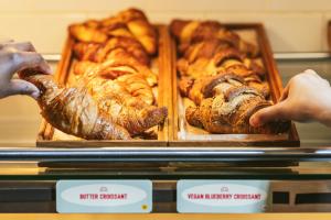 due persone che prendono in mano un vassoio di diversi tipi di pane di Point A Hotel London Shoreditch a Londra