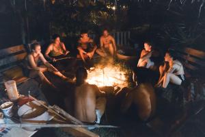 a group of naked people sitting around a fire at ElSueño Ocean view dorm & community vibe in Playa Agua Blanca
