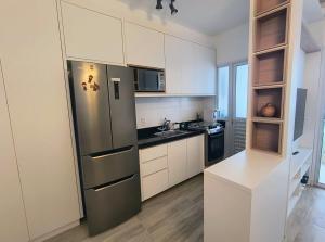 a kitchen with white cabinets and a stainless steel refrigerator at Ocean View JJ in Mongaguá