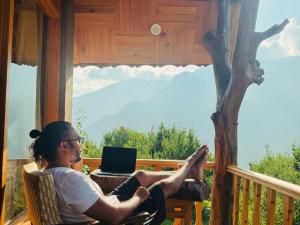 a man sitting on a porch with his feet up on a laptop at Applehill Stays - Work & Relax in Kulu