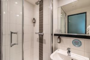 a bathroom with a sink and a shower and a mirror at Point A Hotel London Shoreditch in London +38 photos