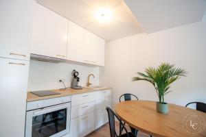 a kitchen with white cabinets and a table with a potted plant at Chambord Apartment Modern comfort near the Loire castles in Courbouzon
