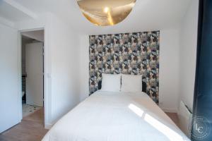 a bedroom with a white bed with a wall at Chambord Apartment Modern comfort near the Loire castles in Courbouzon