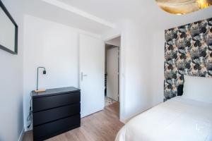 a bedroom with a white bed and a black dresser at Chambord Apartment Modern comfort near the Loire castles in Courbouzon