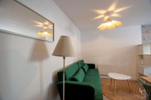 a living room with a green couch and a table at Le Blois Apartment Modern comfort near the Loire castles in Courbouzon