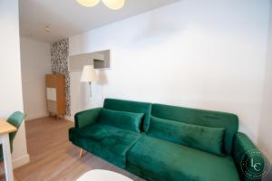 a green couch sitting in a living room at Le Blois Apartment Modern comfort near the Loire castles in Courbouzon +2 photos