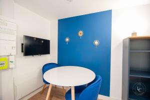 a table and chairs in a room with a blue wall at Le Cheverny Apartment Cozy stay near the Loire castles in Courbouzon