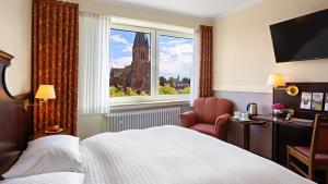 a hotel room with a large bed and a window at Altes Gasthaus Kuhr - Hotel & Restaurant in Papenburg