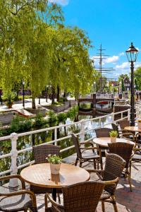 a patio with tables and chairs and a river at Altes Gasthaus Kuhr - Hotel & Restaurant in Papenburg