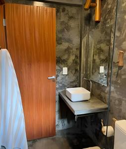 Un baño con puerta de madera y lavabo. en Itacaré Ecolodge, en Itacaré
