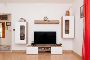 un soggiorno con TV su una parete bianca di Apartment Vrba a Supetar (San Pietro di Brazza)