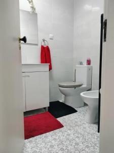 Baño blanco con aseo y alfombra roja en Maré Bela, en Almada 13 fotos más