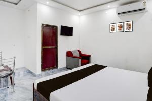 バラナシにあるHotel O Ujala Guest Houseのベッドと椅子とテレビのある寝室