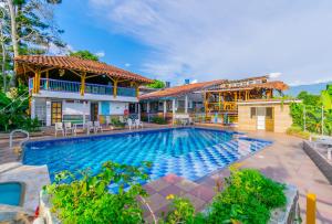 a swimming pool in front of a house at Eco Hotel las Palmas in Armenia