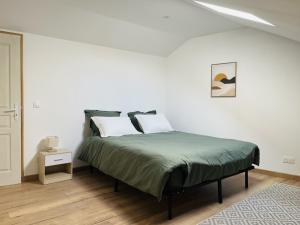 a white bedroom with a bed with green sheets at Le Lodge in Hasnon