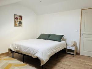 a bedroom with a bed with white sheets and green pillows at Le Lodge in Hasnon