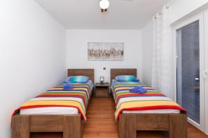 due letti singoli in una stanza con pavimenti in legno di Apartment Vrba a Supetar (San Pietro di Brazza)