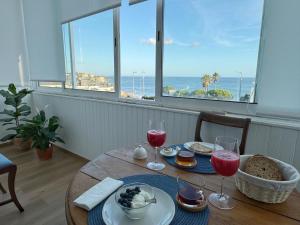 a table with glasses of wine and a view of the ocean at WHome Seaside Getaway Beachfront Apartment in Estoril